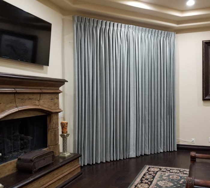 section of a living room with a fireplace and closed drapes