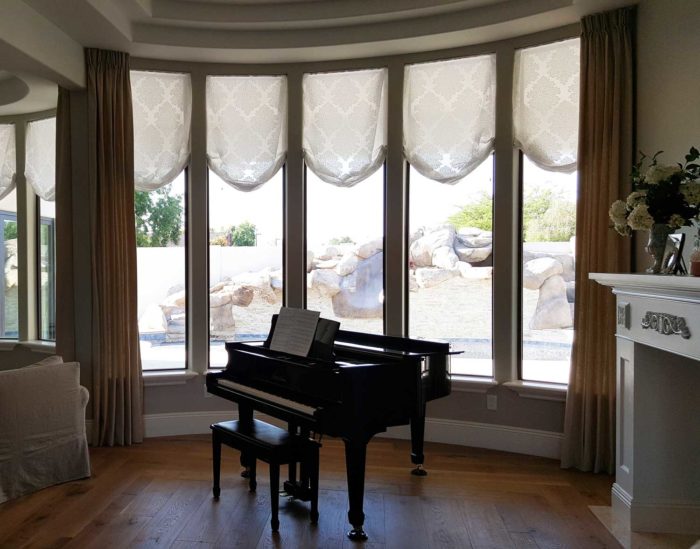 living room corner with piano and full, circular window panels