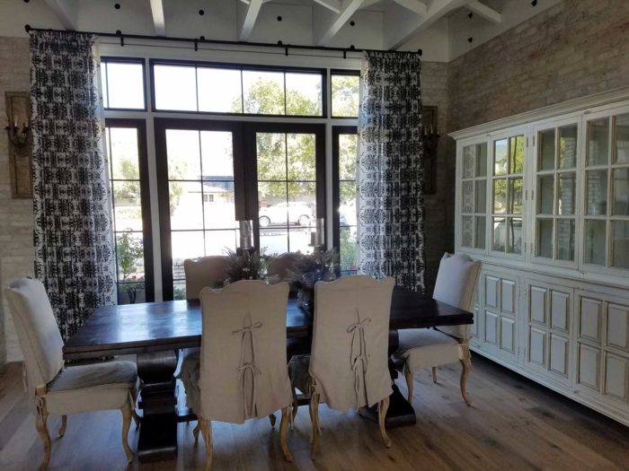 Pleated drapes over a large window in a dining space